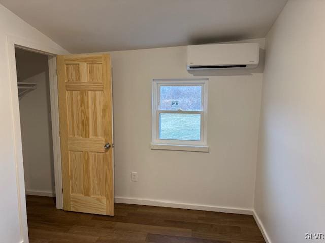 unfurnished bedroom with lofted ceiling, dark hardwood / wood-style floors, and an AC wall unit