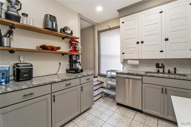 kitchen with gray cabinetry, sink, light stone counters, and stainless steel dishwasher