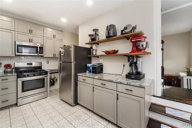 kitchen featuring light stone countertops, appliances with stainless steel finishes, and backsplash