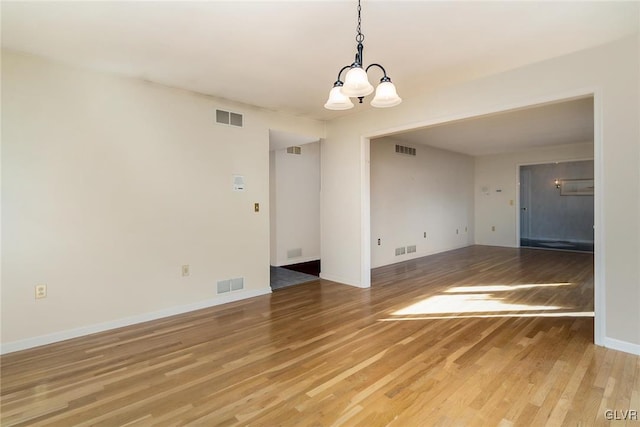 spare room with hardwood / wood-style flooring and a notable chandelier