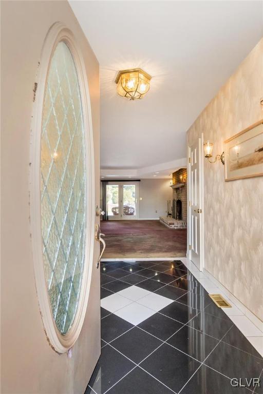 entryway featuring french doors, dark tile patterned flooring, and a brick fireplace