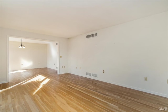 empty room with hardwood / wood-style floors and a chandelier