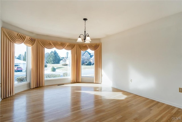 unfurnished dining area with light wood-type flooring and an inviting chandelier