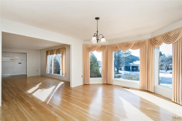 unfurnished dining area featuring a notable chandelier and light wood-type flooring