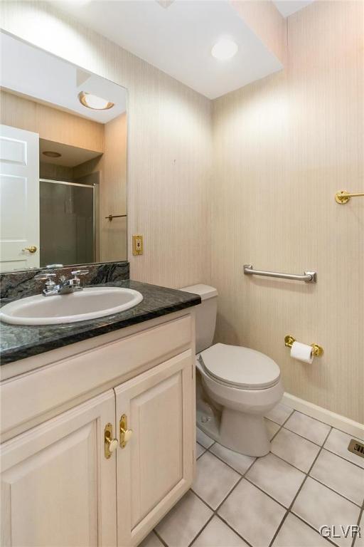 bathroom featuring tile patterned floors, toilet, a shower with shower door, and vanity