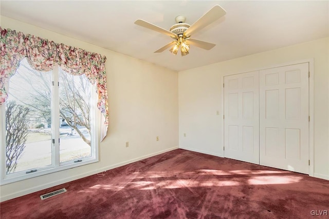 unfurnished bedroom featuring ceiling fan, dark carpet, and a closet