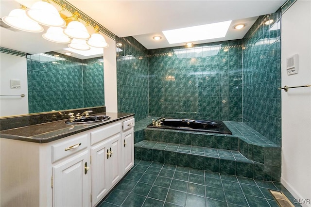 bathroom featuring vanity, a skylight, tile patterned flooring, and tiled tub