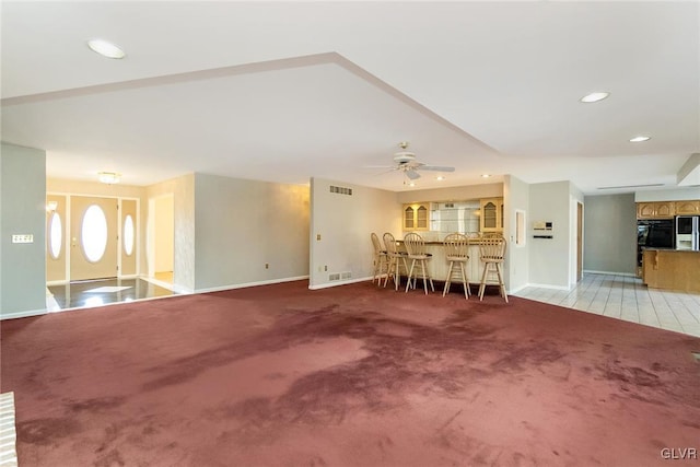 unfurnished living room featuring ceiling fan and carpet