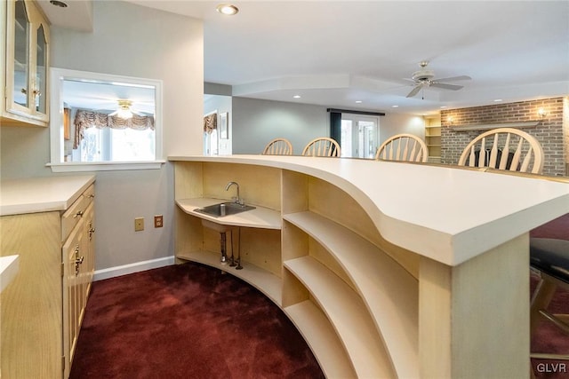 kitchen with a kitchen breakfast bar, kitchen peninsula, ceiling fan, carpet, and cream cabinetry