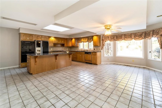 kitchen featuring a kitchen island, a healthy amount of sunlight, backsplash, and black appliances