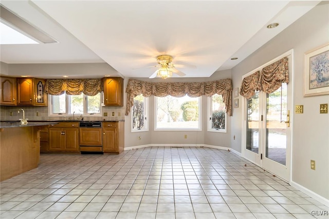 kitchen featuring light tile patterned flooring, sink, dishwasher, ceiling fan, and backsplash