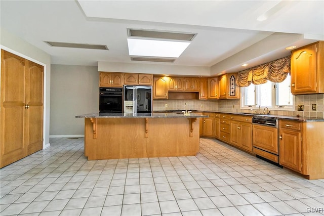 kitchen featuring a breakfast bar area, dishwasher, an island with sink, refrigerator with ice dispenser, and decorative backsplash