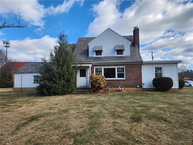 view of front facade featuring entry steps, brick siding, a chimney, and a front yard