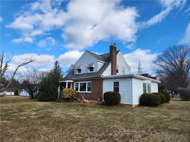 view of home's exterior featuring brick siding, a yard, and a chimney