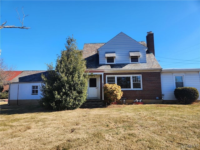 view of front facade featuring entry steps, a front lawn, a chimney, and brick siding