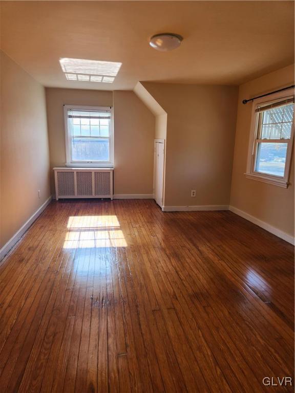 bonus room featuring lofted ceiling, radiator heating unit, and dark hardwood / wood-style floors