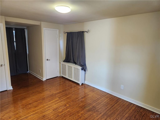 unfurnished room featuring hardwood / wood-style floors and radiator heating unit