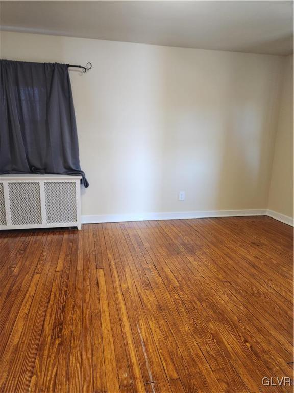 spare room with wood-type flooring and radiator