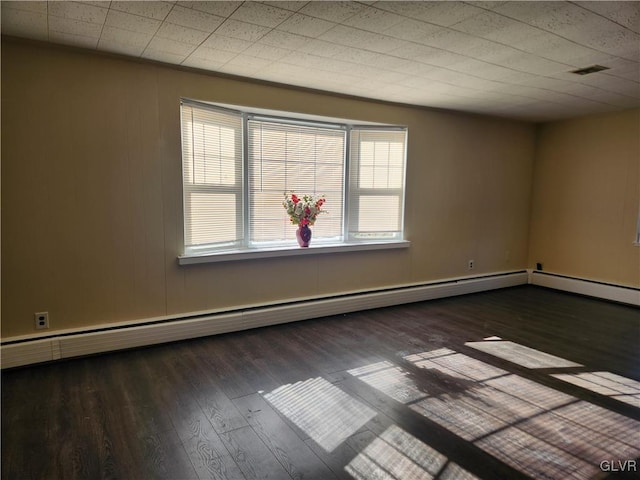 spare room featuring a baseboard heating unit and dark hardwood / wood-style floors