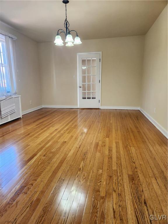 unfurnished dining area with a notable chandelier and light wood-type flooring