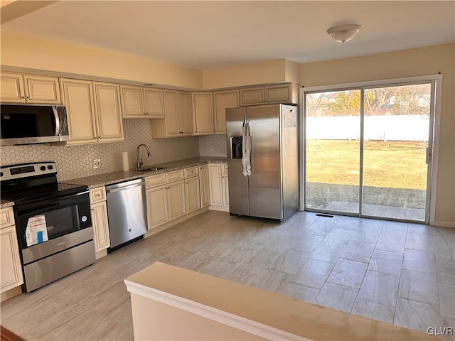 kitchen featuring stainless steel appliances, light stone countertops, sink, and decorative backsplash