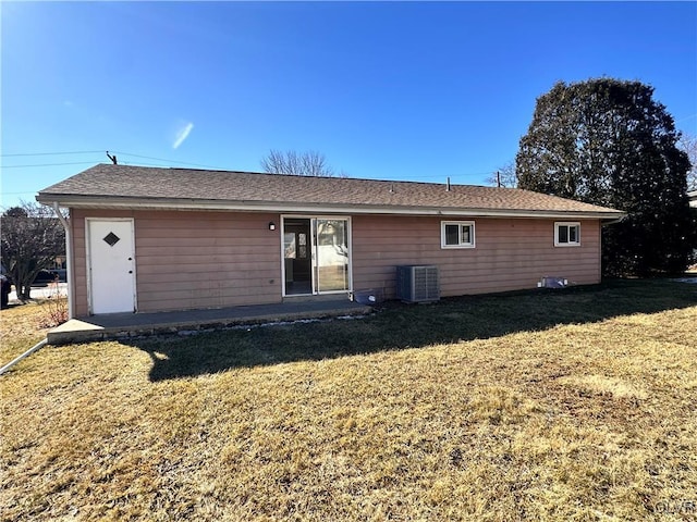 rear view of house with central AC and a yard