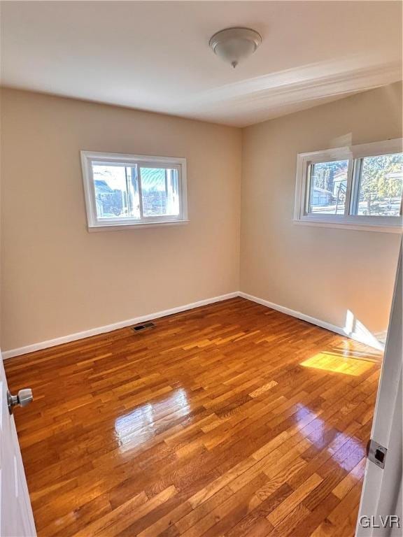 unfurnished room with a wealth of natural light and hardwood / wood-style floors