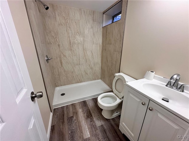 bathroom featuring tiled shower, vanity, toilet, and hardwood / wood-style floors