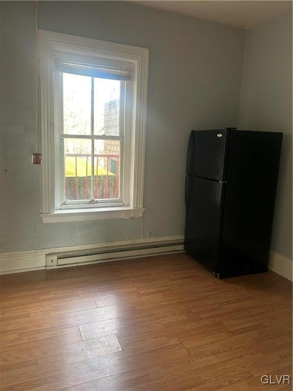 kitchen featuring black fridge, light wood-type flooring, and a baseboard heating unit