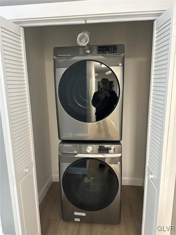 laundry room with stacked washer and dryer and dark hardwood / wood-style floors