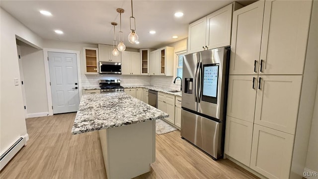 kitchen featuring light stone counters, baseboard heating, appliances with stainless steel finishes, a kitchen island, and pendant lighting