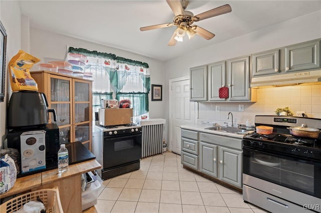 kitchen featuring radiator heating unit, sink, gas stove, and gray cabinetry