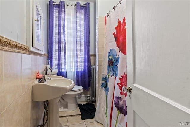 bathroom with toilet, curtained shower, tile patterned flooring, and tile walls