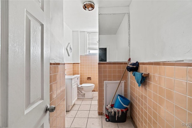 bathroom featuring vanity, toilet, tile patterned flooring, and tile walls