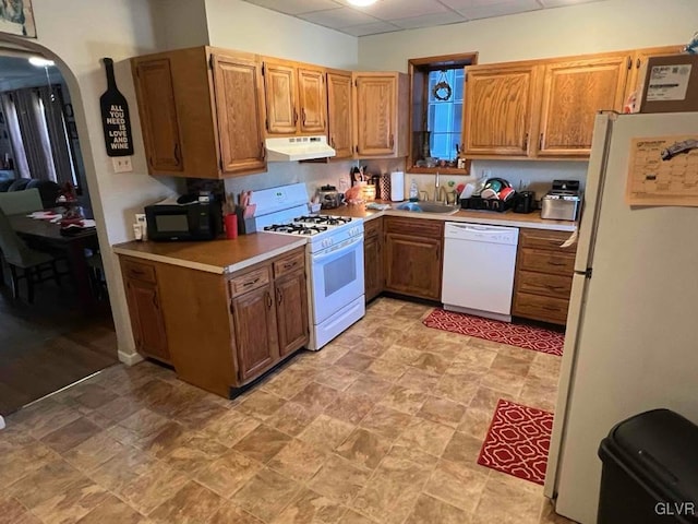 kitchen with white appliances, a paneled ceiling, and sink