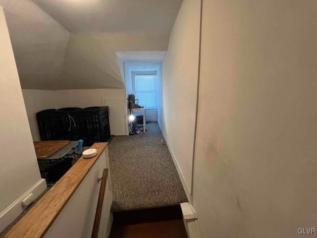 hall featuring lofted ceiling and dark carpet