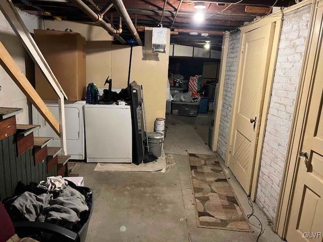 basement with washing machine and clothes dryer and brick wall