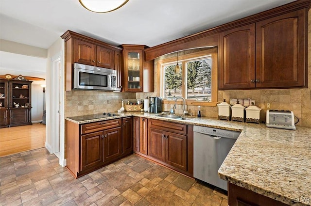 kitchen with tasteful backsplash, sink, light stone counters, and stainless steel appliances