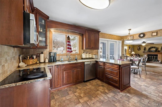 kitchen with sink, light stone counters, decorative light fixtures, appliances with stainless steel finishes, and kitchen peninsula