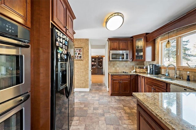 kitchen featuring tasteful backsplash, sink, stainless steel appliances, and light stone countertops