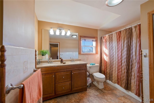 bathroom with vanity, tile walls, and toilet