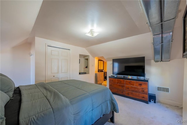 carpeted bedroom with lofted ceiling and a closet