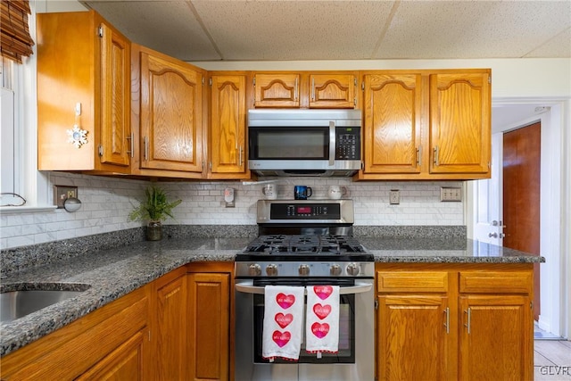 kitchen with tasteful backsplash, sink, stainless steel appliances, and dark stone counters