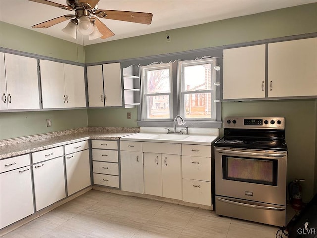 kitchen featuring electric stove, sink, and white cabinetry