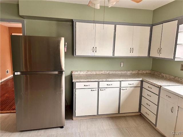 kitchen featuring white cabinets and stainless steel refrigerator