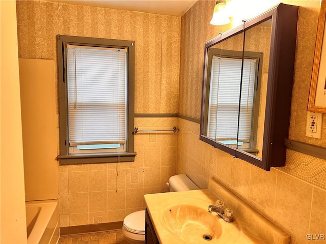 bathroom featuring vanity, toilet, a bathing tub, and tile walls