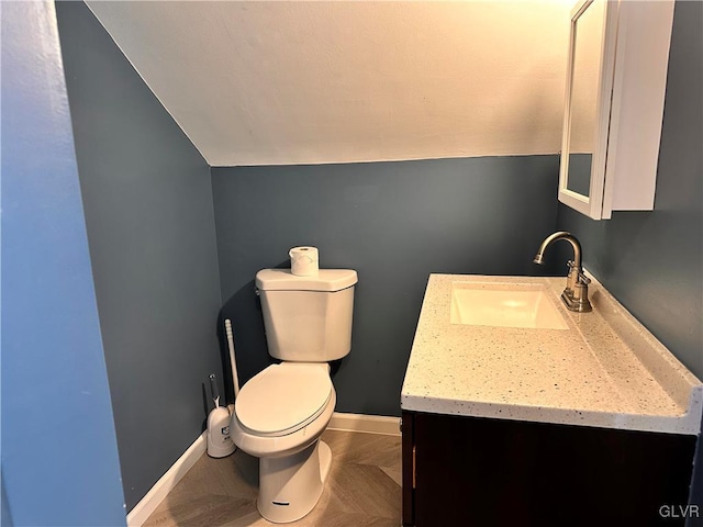 bathroom featuring vanity, lofted ceiling, and toilet