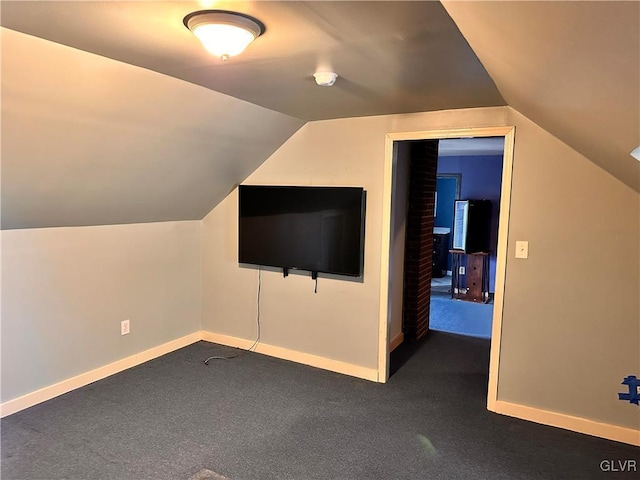 bonus room with dark colored carpet and vaulted ceiling