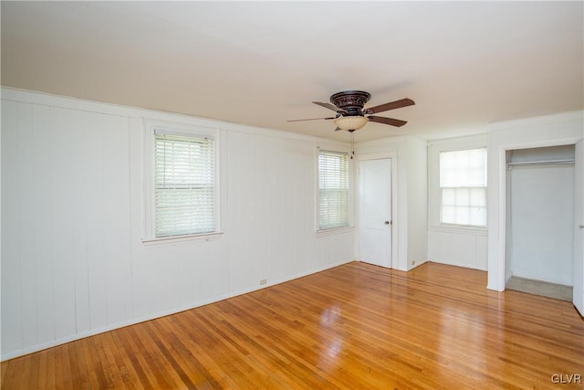 unfurnished bedroom featuring ceiling fan, wood-type flooring, and multiple closets