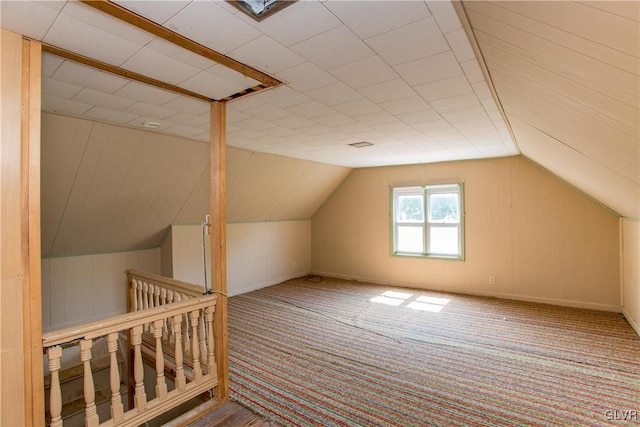 additional living space featuring vaulted ceiling, carpet flooring, and wooden walls